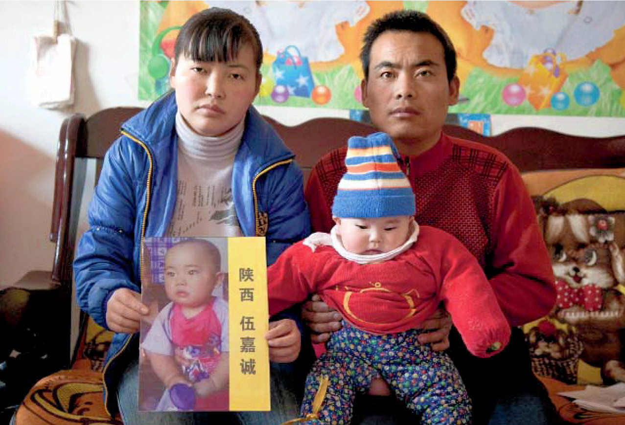 Les parents et la sœur de Jiacheng, dans leur maison près de Xian, en 2011. Sur les genoux de la mère, une photo du petit garçon, enlevé le 10 décembre 2008 à l’âge de 1 an.