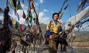 Jeune femme sur un pont orné de drapeaux à prières, près de Paro